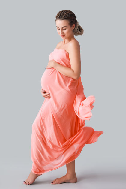 腹部灰色背景的美丽孕妇背景计划年轻