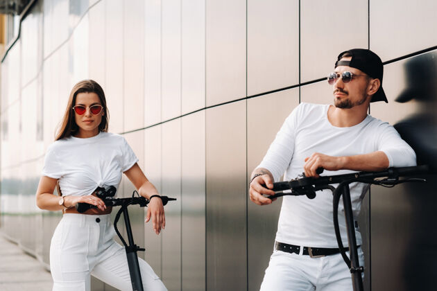电动摩托车一个女孩和一个男孩骑着电动滑板车在城市里走来走去 一对恋人骑着滑板车领域城市生活休闲
