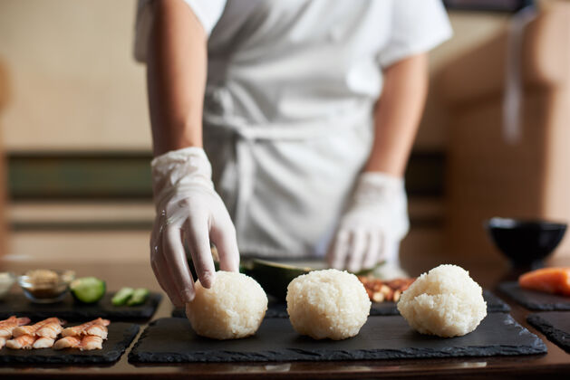 大米在餐厅烹饪滚轴寿司过程的特写镜头厨师正在准备面包卷的配料海鲜生
