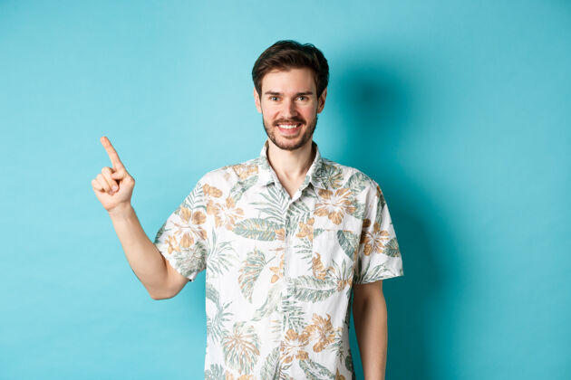 夏威夷人身着夏威夷衬衫的游客微笑着用手指着空旷的空间 展示着标志度假旅游的概念朋友站着人
