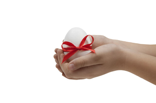 彩蛋白色复活节彩蛋用红丝带绑着 手掌上有一个白色的蝴蝶结手掌复活节红丝带