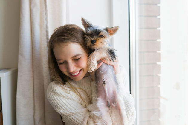 房子周末在家玩狗的年轻女子快乐的约克郡小狗女性微笑玩