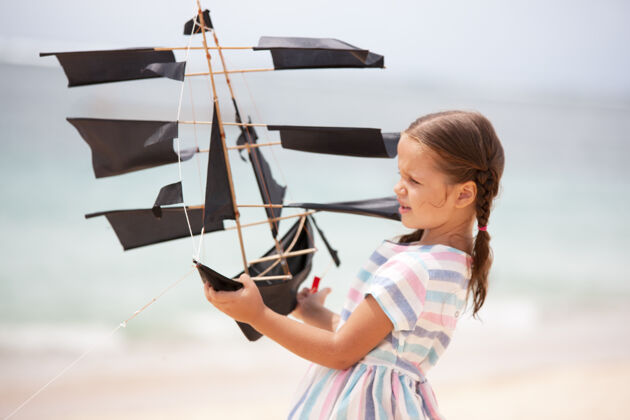 美丽可爱的小女孩在沙滩上玩船风筝情感风筝海边