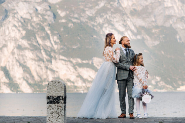 旅游意大利 加尔达湖美丽的家庭在阿尔卑斯山脚下的意大利加尔达湖畔父亲 母亲和女儿在意大利湖泊水欧洲