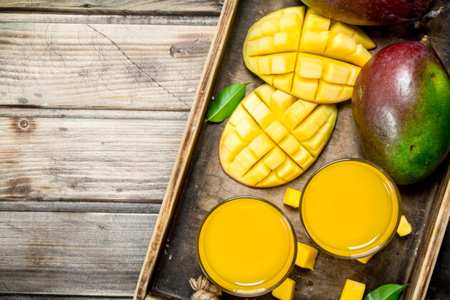 芒果芒果汁放在一个玻璃杯里 放在乡村桌子上的托盘上素食提神营养