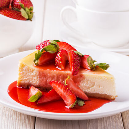 奶酪美味的自制芝士蛋糕和草莓放在白色的木桌上芝士蛋糕草莓营养