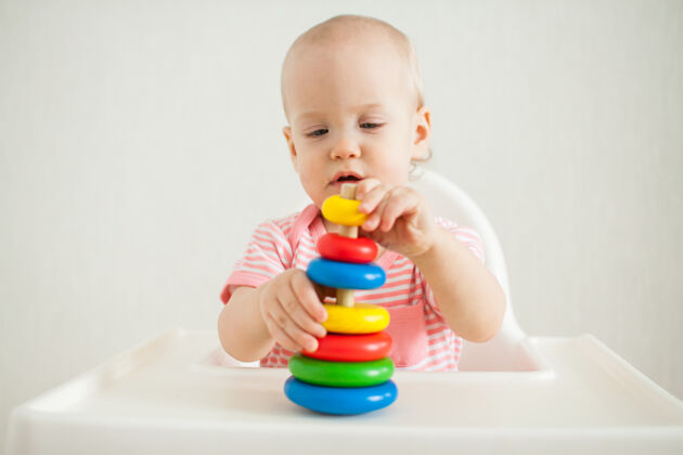技能小女孩玩着一个教育玩具——一个五颜六色的木制玩具金字塔发展太好了教育游戏童年