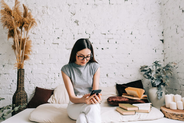 女性戴眼镜的白人年轻女子在家里沙发上休息时使用手机互联网室内休闲