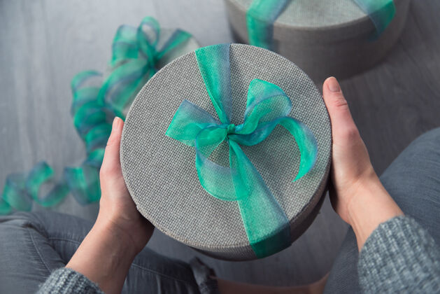 串女人用灰色的圆盒子和绿色的丝带包装礼物女士圆形礼物