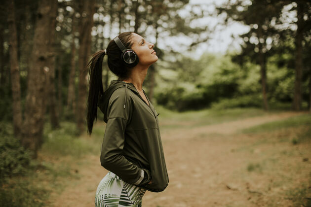 休息在森林里慢跑后 听音乐休息的年轻漂亮的女跑步者运动健康自然