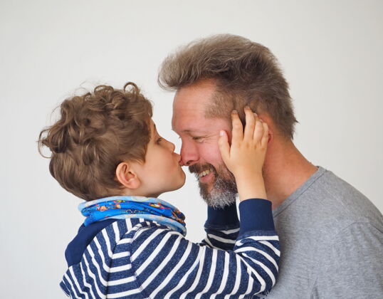 可爱可爱的小男孩亲吻他的父亲父子俩都很开心 面带微笑国际接吻日儿子男人接吻