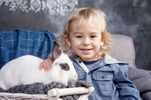 农场可爱的小男孩和一只白色的小狗玩耍兔子男孩微笑着看着镜头童年快乐年轻