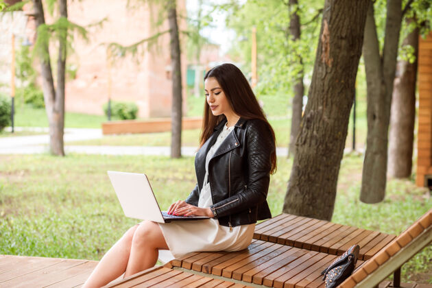 学习美丽的长发女子 学生们正在工作 交流 学习使用她的笔记本电脑在户外公园在夏天坐着长凳女性