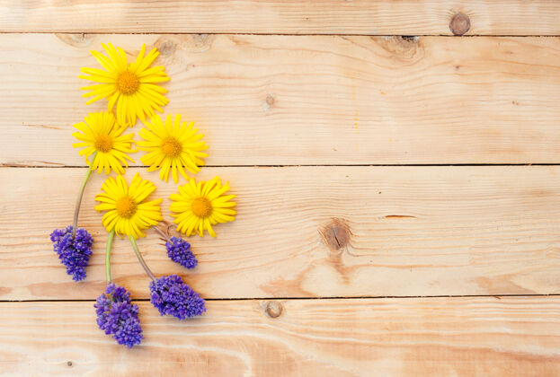 夏天黄色的春花摆在木床上背景.top查看复古花卉空白