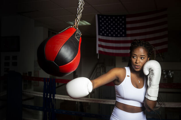 专业年轻的美国黑人女子在体育馆里打着美国国旗训练拳击非洲训练手