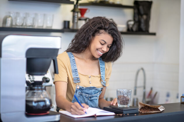 职业乔布微笑专心致志的女人看着咖啡店柜台后面记录咖啡豆确切重量的秤焦点咖啡欢乐