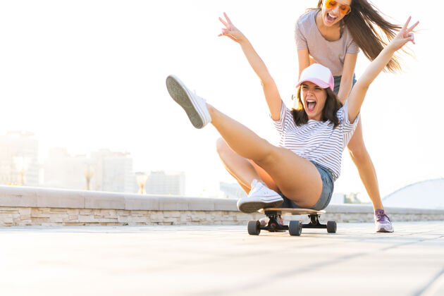 青少年两个微笑的年轻女孩在公园玩滑板漂亮年轻可爱