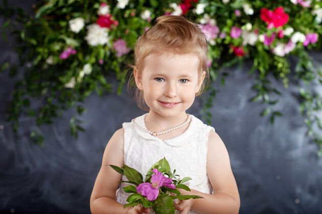 美丽可爱的小女孩带着一束鲜花的肖像花看对着镜头春天亲爱的人