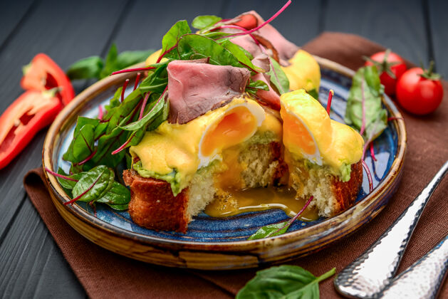 叉子烤面包上的鸡蛋和火腿酱汁早餐在餐厅菠菜培根两个