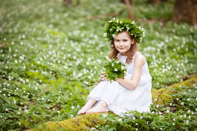 美丽穿着白裙子的漂亮小女孩在春天散步伍德肖像画美丽的小女孩头上戴着春花的花环户外自然举行