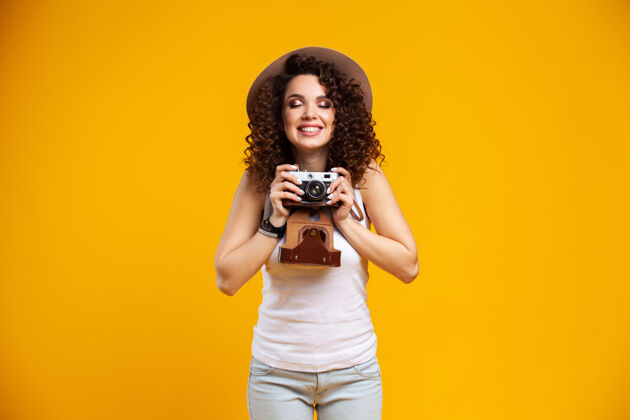 图片在明亮黄色的复古相机上拍摄的笑脸少女肖像女人摄影师时尚