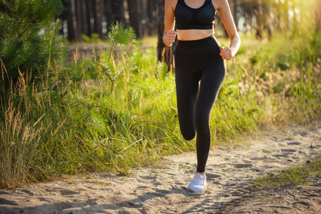 脚一个正在奔跑的女运动员的腿在沙漠中的沙地上森林回来太阳户外健身腿