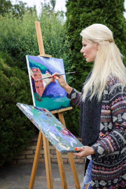 调色板美丽的金发女画家 手里拿着画笔 在大自然的画布上画画女孩女人背景