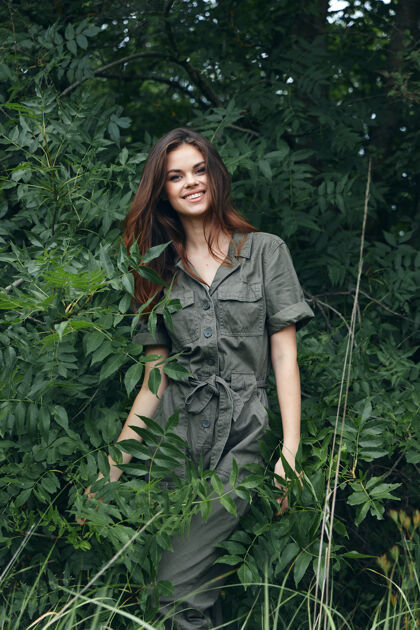 皮肤女人在森林附近的绿色灌木丛里 一脸灿烂的笑容 一身绿色的连身衣 绿叶丛生 尽收眼底年轻性感新鲜