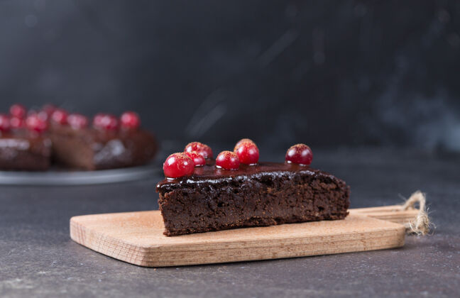 美味一块无麸质的巧克力蛋糕 在厨房的黑板上装饰着小红莓背景健康吃东西复制空间特写奶油巧克力饼