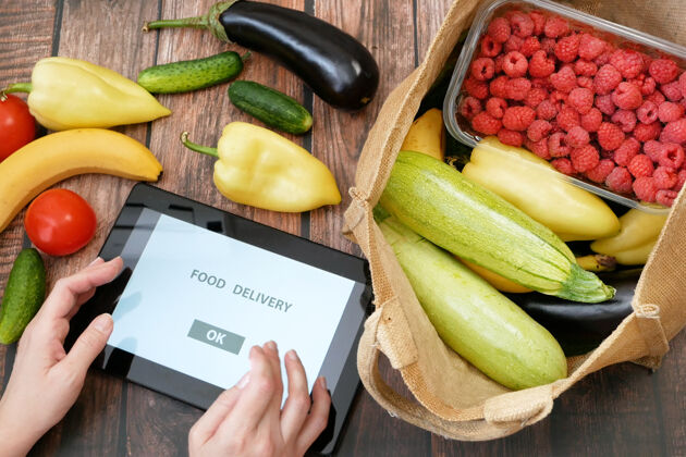 平板电脑有机蔬菜和水果在棉袋和平板电脑 网上市场 绿色杂货送货概念黄瓜在线包