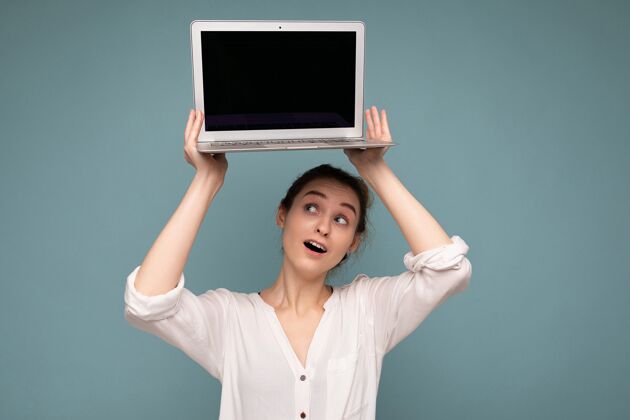 数字美丽的微笑快乐的年轻女子拿着电脑笔记本 抬头看着上网本 穿着休闲的智能衣服 隔着墙玩得很开心背景.mock起来 复制空间 剪掉工作便携式计算机