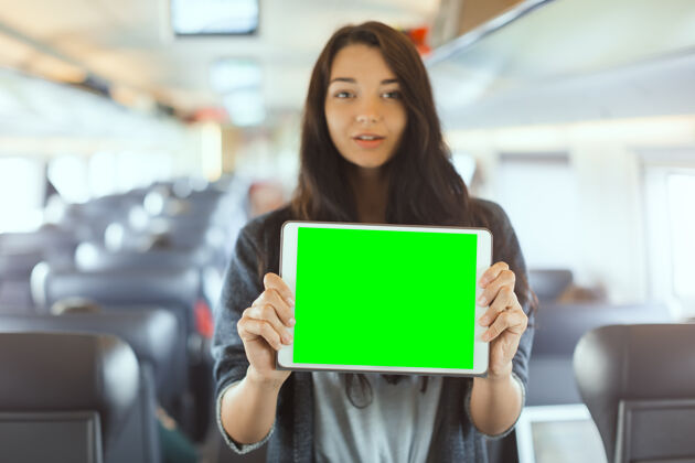概念年轻的女游客手持平板电脑旅行火车旅行应用概念交通生活方式火车