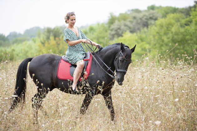 骑马骑马的姑娘正骑着她的黑马走呢金发头发马