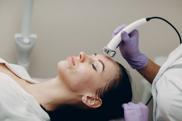 清洁在美容spa沙龙接受电穿孔透声面部治疗的女性头像特写工具沙龙护理