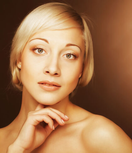 女人漂亮的年轻女子 金色的头发披挂在米色的墙上魅力化妆模特