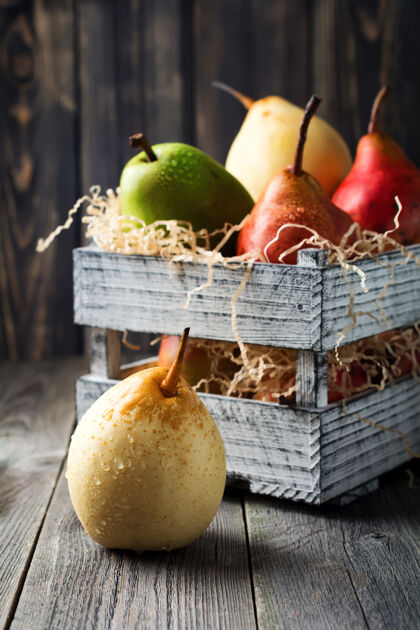 配料红的 绿的 黄的 甜的梨和一个苹果放在一个深色的旧木箱里纤维法国果糖