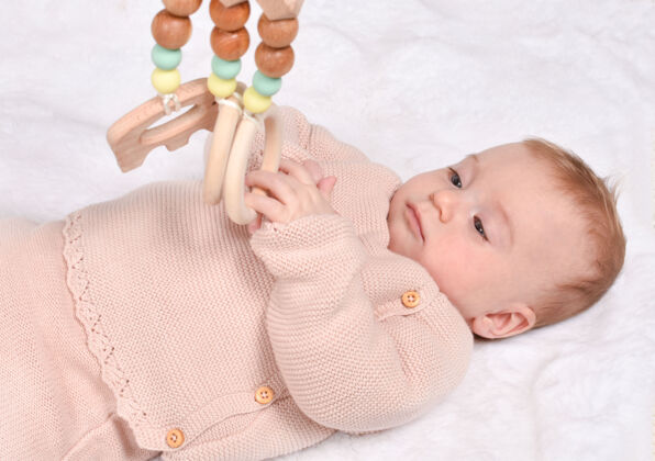 婴儿可爱的小白种人宝宝玩环保木制玩具 仰卧着金发婴儿三个月