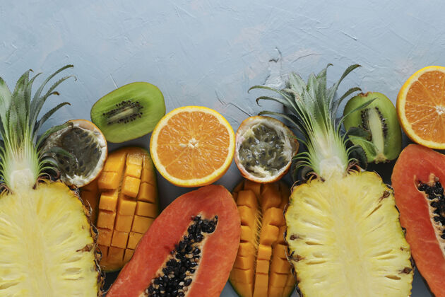 切片一半的热带水果：木瓜 芒果 菠萝 猕猴桃 橘子和西番莲果在浅蓝色的表面 俯视图 水平格式泰国异国情调菠萝