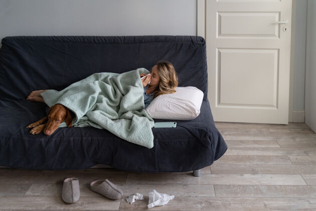 房子生病的女人在家和她的狗躺在床上 患有过敏 流感症状 发烧毯子成人枕头