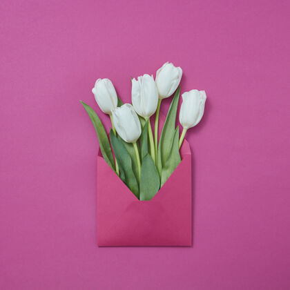 花紫色背景上的白色郁金香手工信封的祝贺贺卡文本.平面躺下工艺手工制作花