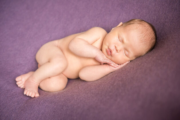 新生儿赤裸的新生婴儿睡在紫色的墙上童年女性宁静