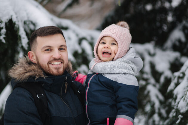 美丽可爱的小女儿和她可爱的爸爸站在雪树旁生活方式散步有趣