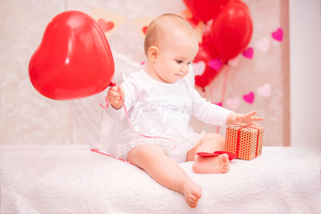 饼干一个长着白色羽毛翅膀的孩子手里拿着一个心形的红色气球 看到一个盒子里装着礼物 象征着情人节幼儿人奇迹