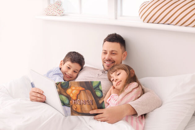 肖像爸爸和他的小孩在家里读睡前故事睡衣睡眠舒适