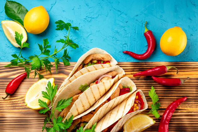 酸橙拉丁美洲玉米饼 鸡肉和玉米放在木板上 蓝色背景特写墨西哥玉米卷香菜认证