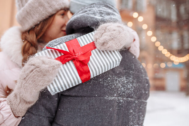 乐趣一位年轻女子双手搂着男友的脖子 抱着因为冬季公园情人节礼物而高兴的心情外面爱 幸福 团聚和约会的概念女性情侣雪