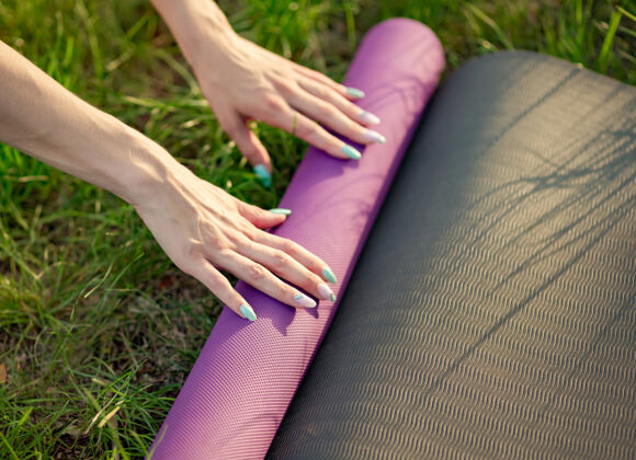 私人教练女性将瑜伽垫放在草地上的剪短图像运动水平运动