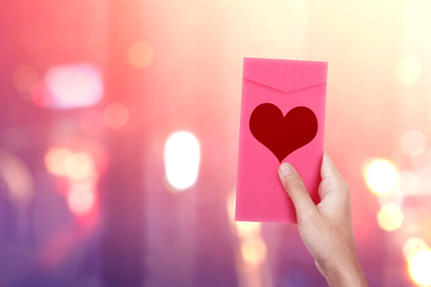 节日人的手拿着一个心形的粉色信封 光线模糊不清墙情人节礼物天哪情人节礼物季节