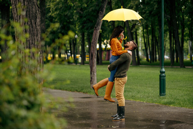 情人一对幸福的情侣在夏雨中拥抱戴曼雨中的女人在雨伞下拥抱 散步路上的浪漫约会 巷子里的潮湿天气约会人快乐