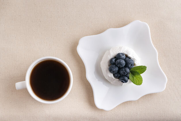 特写一杯咖啡和蛋白糖浆果蛋糕.上衣视图早餐在床上蓝莓蛋白酥皮茶
